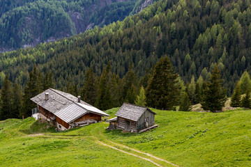 eine kleine Berghütte aus Holz, im Hintergrund Berge