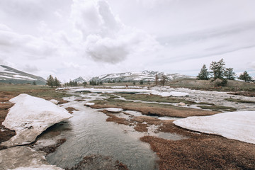 naked tourist in shorts with a backpack goes to the mountains. The snow around