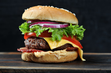 Cheeseburger with bacon on a dark background. Close-up. Macro shooting.