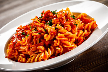 Pasta with tomato sauce and vegtables on wooden table