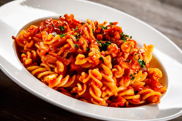 Pasta with tomato sauce and vegtables on wooden table