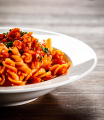Pasta with tomato sauce and vegtables on wooden table