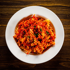 Pasta with tomato sauce and vegtables on wooden table