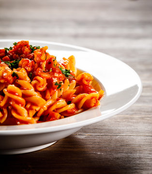 Pasta with tomato sauce and vegtables on wooden table