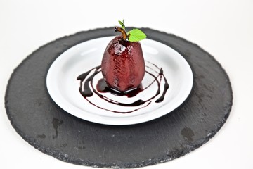 Poached pear in red wine and cinnamon on plate