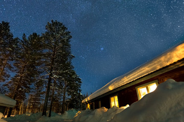 Winter landscape with wooden house under a beautiful starry sky