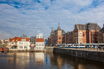 Fototapeta na wymiar Canals, central railway station and tram at the Old Central district of Amsterdam