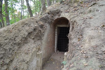 Excavated tunnel and gate in an earthen city fortification in Leuven, Belgium. The fortification does not have a door but is closed by means of metal bar grating.