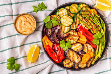 Grilled vegetables on a plate with sauce.