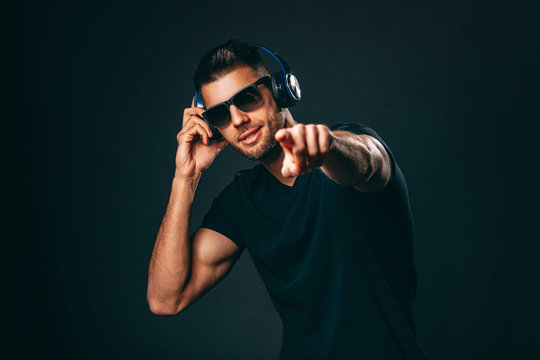 Handsome man with headphones in studio on dark background