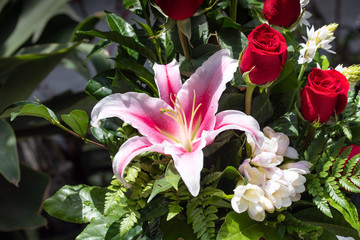 Ramo de flores con lirio rosado, rosas y hojas verdes