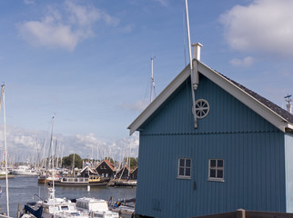 Fototapeta na wymiar Blaues Gebäude aus Holz im Hafen von Hindeloopen Ijsselmeer in Niederlande.