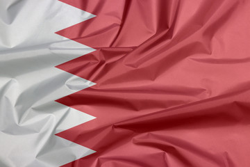 Fabric flag of Bahrain. Crease of Bahraini flag background, five white triangles in the form of...