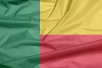 Obraz premium Fabric flag of Benin. Crease of Beninese flag background, A horizontal bicolor of yellow and red with a green vertical band.