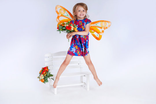 Girl in butterfly costume. Child posing in studio. Girl with butterfly wings. Baby and flowers. Fly of butterfly..