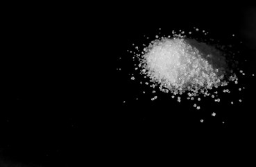 small pile of white sugar in side view on a black background