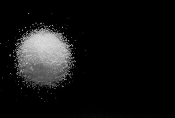 small pile of white sugar in side view on a black background