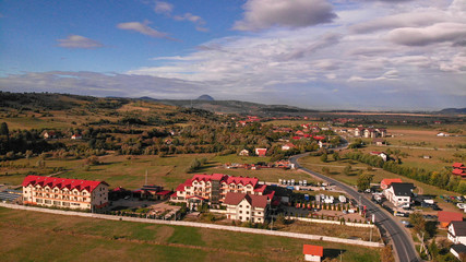 Naklejka premium Aerial view of Bran town near the Bran castle in Transylvania, Romania, Brasov region. Cloudy day with beautiful clouds.