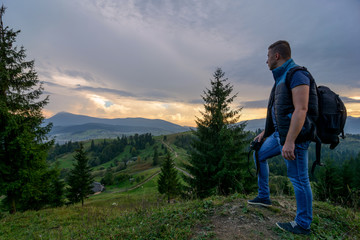 A tourist in the middle of the mountains looks at the sunset. Nature, travel, tourism 