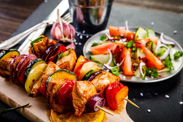 Kebabs - grilled meat with french fries and vegetables on wooden background