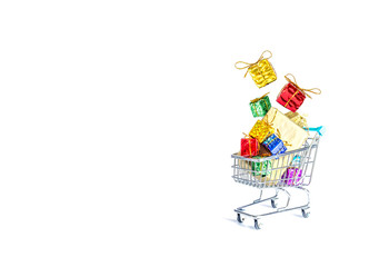 Multicolored gift boxes with beautiful golden bows fall into a gift-filled shopping cart isolated on a white background