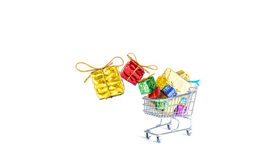 Multicolored gift boxes with beautiful golden bows fall into a gift-filled shopping cart isolated on a white background