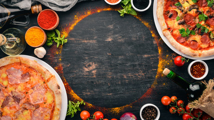 A set of Italian pizza. Italian cuisine. On a black wooden background. Free copy space. Top view. - obrazy, fototapety, plakaty