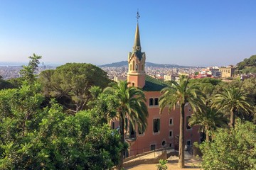 Fototapeta premium fairy-tale house with a tower, pink building with a tower and spire, sunny warm weather, panorama of the city, many plants