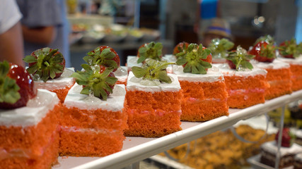 Restaurant Buffet. In the foreground there are plates with dessert. In the background, defocused citizens choose food.