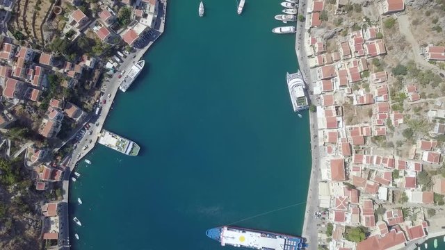 Aerial footage of the beautiful island of Symi (Simi) with Colorful houses and small boats at the heart of the village bay.