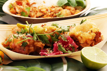 various street food with chicken wings on rustic background. balinese nasi campur and indian and brasilian street food.