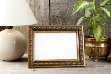Empty brass picture frame on wooden background.