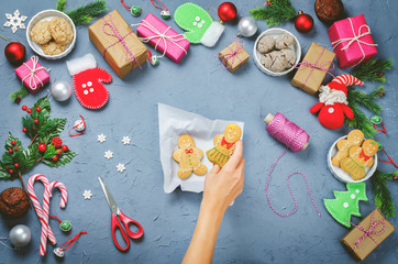 Fototapeta na wymiar Christmas background with gifts, cookies, Christmas decoration and woman's hands holding cookies