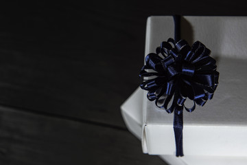 christmas white gift box with a blue bow on a black background from boards with  copyspace