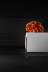 christmas white gift box with a red bow on a black background from boards with copyspace
