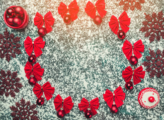 Christmas or new year composition. Round frame made of christmas balls and bows decoration on background of snow with space for text. Top view