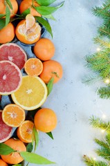 Oranges, tangerines, lemons, grapefruit with leaves and branches of a Christmas tree. Christmas lights, New Year, concept, copy space. Composition from fresh citruses. Festive mood, holidays