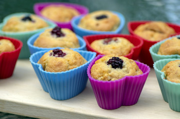Banana muffins with chocolate, blackberries, strawberries, nuts and raisins in silicone molds on wooden mat, colorful hearts