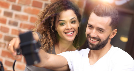 Happy cheerful couple sitting down at a cafe and making selfie