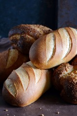 Delicious freshly baked bread on wooden background. Bakery product assortment with bread loaves, buns, rolls. Different kinds of bread 