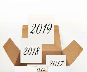 Cards with 2019, 2018 etc. years in opened cardboard box , on white background