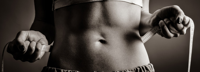 Beautiful and strong women's abs with metre. Image in black and white style