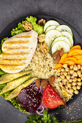 Bowl of Buddha, The concept of a healthy diet: grilled chicken, avocado, chickpeas, kinua, carrots, tomatoes, nuts. Balanced food. Top view. Copy space.