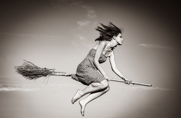 Young witch on broom flying away. Image in black and white color style