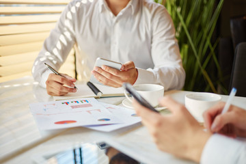 Crop hardworking businessmen in cafe