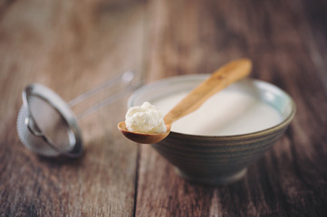 Kefir Grains on Wooden Spoon with a Cup of Kefir and a Strainer in background. Homemade Organic...