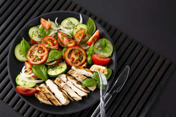 Vegetable salad and grilled chicken on a black background. Healthy food. Diet. Сopiespace.