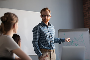 Confident speaker, team leader, business coach giving presentation explaining growing graph to...