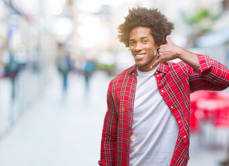 Afro american man over isolated background smiling doing phone gesture with hand and fingers like talking on the telephone. Communicating concepts.