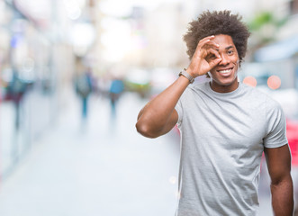 Fototapeta premium Afro american man over isolated background doing ok gesture with hand smiling, eye looking through fingers with happy face.
